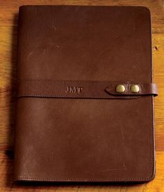 a brown leather journal sitting on top of a wooden table