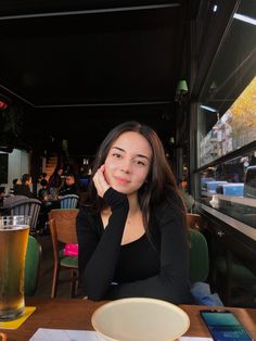 a woman sitting at a table with a glass of beer