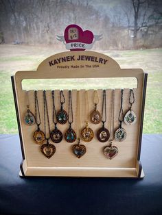 a display case with many different necklaces hanging from it's sides on a table