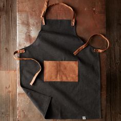 the apron is made from canvas and has two leather straps on one side, while the other