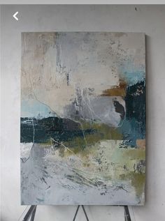 an abstract painting is displayed on a easel in front of a white wall and floor