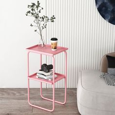 a pink side table with books and a plant on it next to a white couch