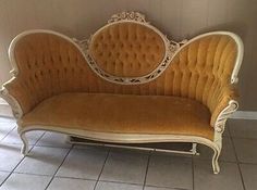 an old fashioned couch sitting on top of a tile floor in front of a wall