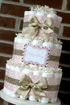 a pink and gold diaper cake with polka dots, bows and a name on it