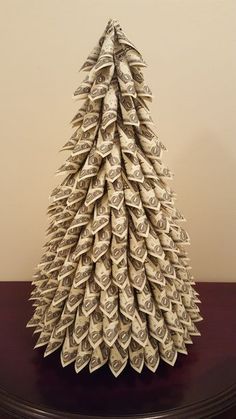 an origami christmas tree made out of one hundred dollar bills on a table