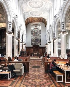 two people sitting on couches in a large church with high ceilings and stained glass windows