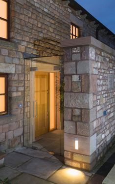 an entrance to a stone building lit up at night with lights on the door and windows