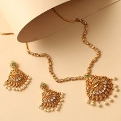 Description This traditional classic necklace Mishi antique necklace set is a classic statement design to pair with any traditional attire. Featuring lakshmi motif in the center studded with kempu stones & gold ball drops, this all-around necklace gives shine to the overall look. Pair it with any simple or heavy ethnic attire to complete the Indian look. Details & Specifications: Materials used: Brass Alloy with Antique Gold Plating Weight - Necklace: 30 gms, Earrings: 16 gms Length - Necklace: Kundan Temple Necklace With Latkans, Gold Kundan Necklace With Meenakari, Gold Kundan Necklace For Festive Anarkali Style, Diwali Temple Necklace With Stone Work, Navratri Temple Jewelry Necklace With Stone Work, 30 Gms Gold Necklace, 30 Gms Gold Necklace Set, Antique Necklace Set, Indian Look