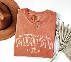 Celebrate your little pumpkin's arrival with our pregnancy announcement 2025 Comfort Colors shirt! Perfect for a fall-themed baby reveal, this adorable tee is a sweet way to share your exciting news. Whether it's a Thanksgiving surprise or a fun mommy-and-me moment, this shirt is designed to make your announcement extra special. A must-have for moms-to-be, it's available in various sizes and colors to fit your fall style.  Check out the matching "Mommy's Little Pumpkin" baby bodysuits here: http Little Pumpkin Pregnancy Announcement, Maternity Shirts Vinyl Thanksgiving, Thanksgiving Maternity Shirt, Thabksgiving Pregnancy Shirts, Thanksgiving Baby Announcement, Pregnant Thanksgiving Shirt, Thanksgiving Baby, Pumpkin Thanksgiving, Pregnancy Announcement Shirt