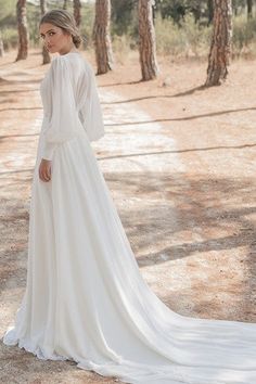 a woman in a white wedding dress standing on a dirt road surrounded by palm trees