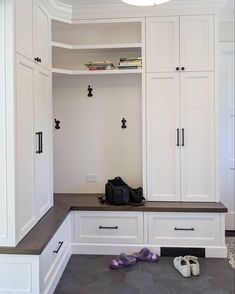 a closet with white cabinets and shoes on the floor