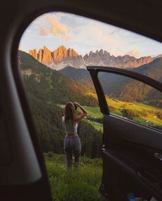 a woman looking out the window of a car at mountains and valleys in the distance