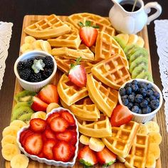 a wooden tray topped with waffles and fruit