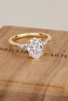 a diamond engagement ring sitting on top of a wooden box with the words brilliant earth written across it