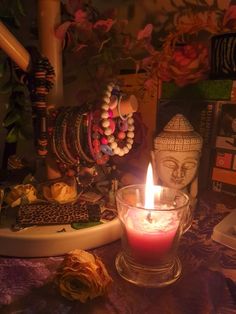 a candle sitting on top of a table next to some beads and other things in front of it