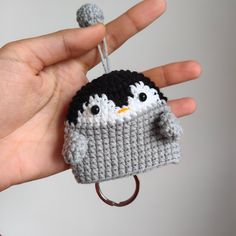 a small crocheted penguin keychain is being held by someone's hand