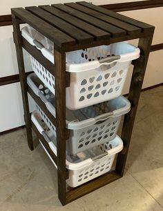 three white laundry baskets stacked on top of each other in front of a wooden shelf