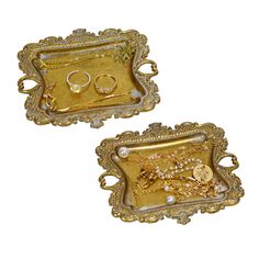 two gold trays with rings on them and pearls in the middle one is empty