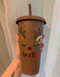 a person holding up a cup with reindeer faces on it