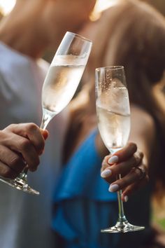 two people holding wine glasses in their hands