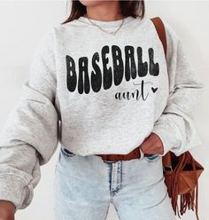 ABOUT OUR Baseball Aunt Sweatshirt: PRODUCTION TIME: 1-3 days (Usually 2 days) SHIPPING TIME: 2-5 days (Usually 3 days) PRODUCT DESCRIPTION: Gildan 18000 Sweatshirt Super soft cotton and excellent quality print makes. 100% Soft cotton (fibre content may vary for different colors) Light fabric (4.2 oz/yd² (142 g/m Runs true to size Our Relaxed Fit Sweatshirt (Gildan 18000) is a unisex style that runs a touch small for men, and about a half a size large for women. It's a relaxed fit and is soft and cozy. * For T-shirt Sizes Please refer to the Listing Image. CARE INSTRUCTION: Machine wash: warm (max 40C or 105F); Non-chlorine: bleach as needed; Tumble dry: low heat; Iron, steam or dry: medium heat; Do not dryclean PRINTING METHOD: DTG printing method is used for these shirts. A process of pr Athletic Heather Long Sleeve T-shirt With Letter Print, Long Sleeve Graphic T-shirt For Baseball Season, Long Sleeve T-shirt With Graphic Print For Baseball Season, Long Sleeve Graphic Print T-shirt For Baseball Season, Heather Grey Crew Neck Top Fan Apparel, Heather Grey Crew Neck Fan Apparel Top, Heather Grey Crew Neck Top For Sports Season, Sports Season Crew Neck Tops With Lettering, Cotton Slogan Top For Baseball Season