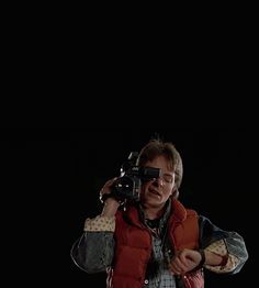 a man holding a camera up to his face in front of a black background,