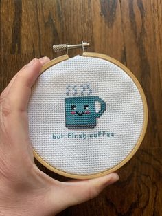 someone is holding up a cross - stitched mug with the words coffee on it