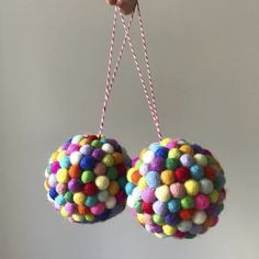 two colorful balls hanging from strings in the air with one being held by a hand