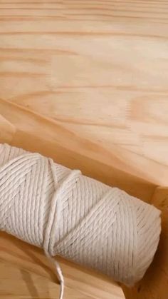 a roll of white rope on top of a wooden table next to a piece of wood