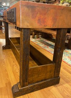 an old wooden table with drawers on it in a room filled with wood flooring