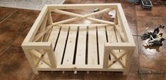 a wooden bed frame sitting on top of a floor next to a pile of tools