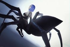 a woman with blue hair sitting on top of a spider