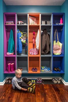 a little boy sitting on the floor in front of a colorful closet with shoes and bags