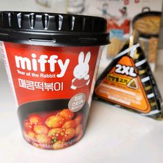 a plastic cup filled with food sitting on top of a white counter next to a bag of chips