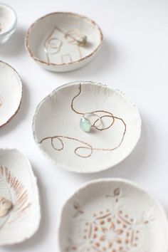 several white bowls with designs on them sitting next to each other and one has a ring in the middle