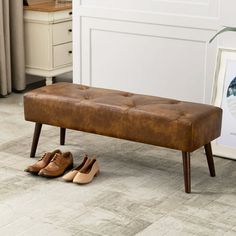 a pair of brown shoes sitting on top of a wooden bench next to a painting