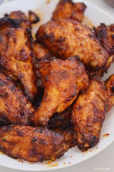 some chicken wings on a white plate ready to be eaten with sauce and seasoning