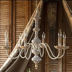 a white chandelier hanging from a wooden ceiling