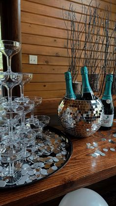 there are many wine glasses and champagne bottles on the table with silver confetti