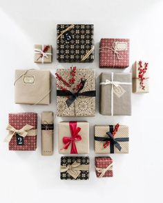 many wrapped presents are arranged in the shape of a heart on a white surface with red ribbon