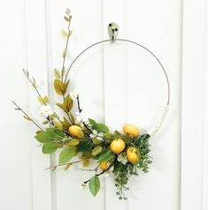 a wreath with lemons and greenery hangs on a white door frame against the wall