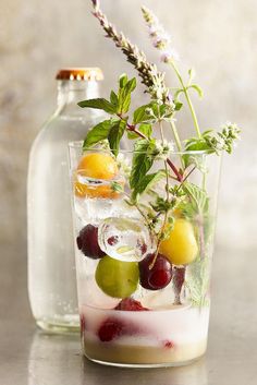 a glass filled with ice and fruit next to a bottle