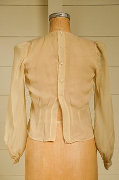 "Antique Silk Blouse Sheer Ivory Button Back Pleated Deco Blouse Beautiful silk blouse. Pleated front with a fitted waistline. Back has metal snap closures with pearl button coverings. Shows normal signs of wear. Measurements shoulders: 13 3/4'' chest: 36\" waist: 33\" length: 20\" sleeve: 23''" Classic Fitted Blouse With Button Closure, Formal Fitted Blouse With Back Button Closure, Fitted Classic Blouse With Covered Buttons, Elegant Button-up Blouse With Pearl Buttons, Elegant Button-up Tops With Pearl Buttons, Classic Blouse With Pearl Buttons, Classic Formal Blouse With Pearl Buttons, Long Sleeve Blouse With Button Closure For Wedding, Workwear Blouse With Pearl Buttons