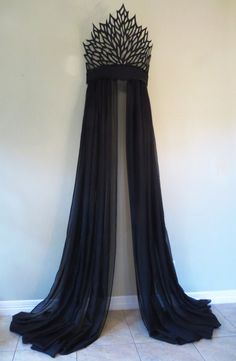 a black dress hanging up against a wall with a crown on it's back