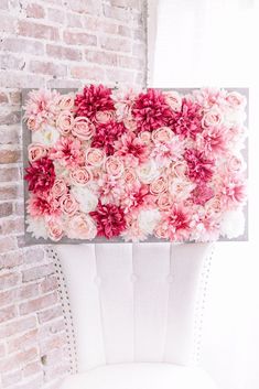 a white chair sitting in front of a brick wall with pink flowers on the back