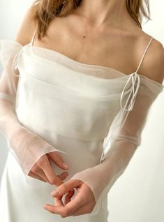 a woman in a white dress is holding her hands together