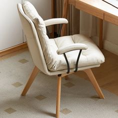 a white chair sitting on top of a wooden floor next to a desk with a laptop computer