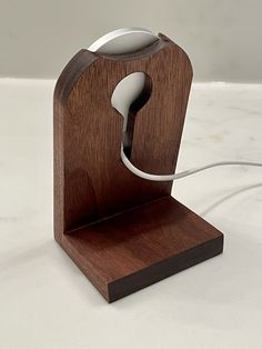 a wooden desk lamp with a white light on top of it and a cord plugged into the base