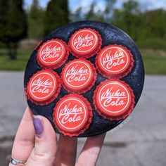 a person holding up six coca cola bottle caps