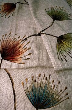 two pieces of cloth with flowers on them sitting on top of a tablecloth that has been embroidered onto it